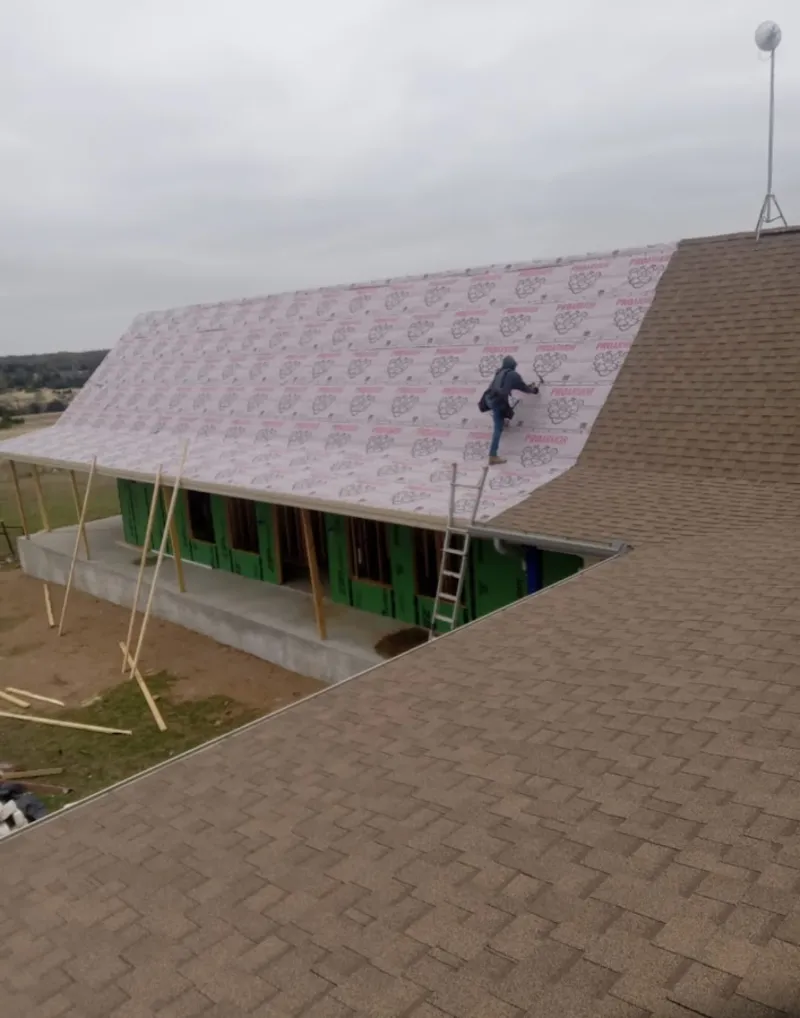 Worker preparing underlayment for a metal roof installation in Page
